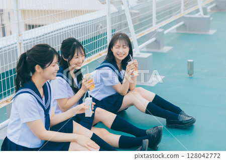 Three high school girls chatting on the roof of the school building 128042772