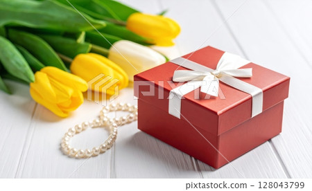 Surprise red gift box with golden ribbon and tulips for birthday or Christmas celebration Surprise red gift box with golden ribbon and tulips for birthday or Christmas celebration 128043799