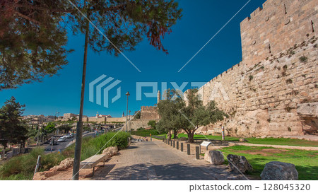Defensive wall of the ancient holy Jerusalem timelapse hyperlapse, lit by the bright sun. Wonderful green lawn 128045320