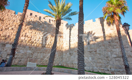 Defensive wall of the ancient holy Jerusalem timelapse hyperlapse, lit by the bright sun. Wonderful green lawn Defensive wall of the ancient holy Jerusalem timelapse hyperlapse, lit by the bright sun. Wonderful green lawn 128045322