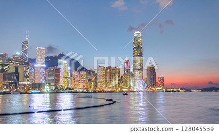 Hong Kong, China skyline panorama with skyscrapers day to night from across Victoria Harbor timelapse. 128045539