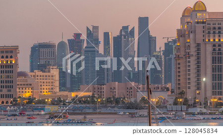 View from Katara Beach day to night timelapse in Doha, Qatar, towards the West Bay and city center View from Katara Beach day to night timelapse in Doha, Qatar, towards the West Bay and city center 128045834