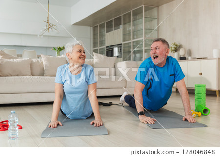 Fitness workout training. Senior adult mature healthy fit couple doing sports exercise on yoga mat on floor at home. Mid age old husband wife have training workout. Health care healthy lifestyle 128046848