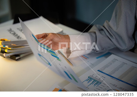 Late Night Analysis. Professional reviewing financial graphs and reports. Late Night Analysis. Professional reviewing financial graphs and reports. 128047335