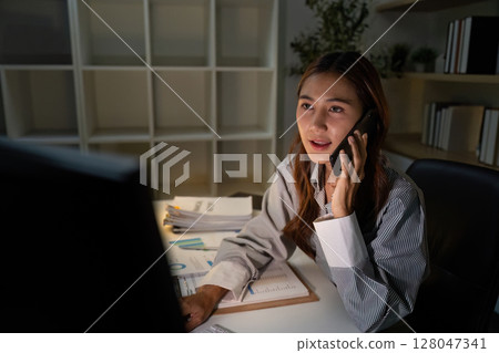 Late Night Communication. Professional woman on phone discussing financial matters. Late Night Communication. Professional woman on phone discussing financial matters. 128047341