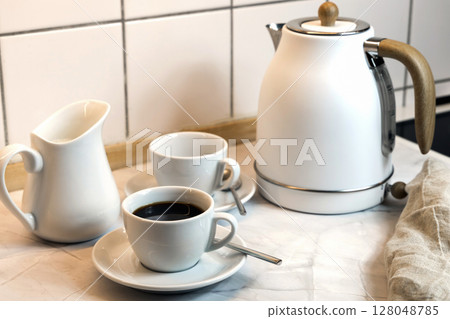 Breakfast served on the kitchen table with coffee cup and kettle Breakfast served on the kitchen table with coffee cup and kettle 128048785