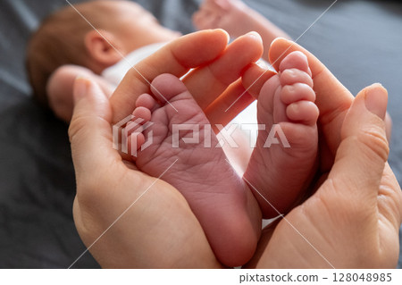 Tender Moment: Adult Hands Holding Newborn Baby Feet 128048985