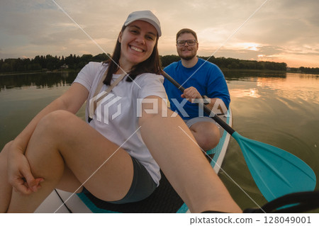 Couple Paddleboarding at Sunset 128049001