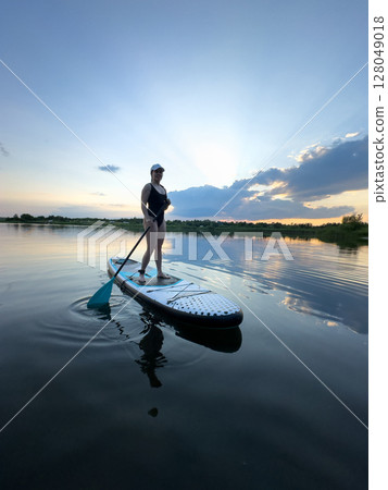 Paddleboarding at Sunset on a Tranquil Lake 128049018