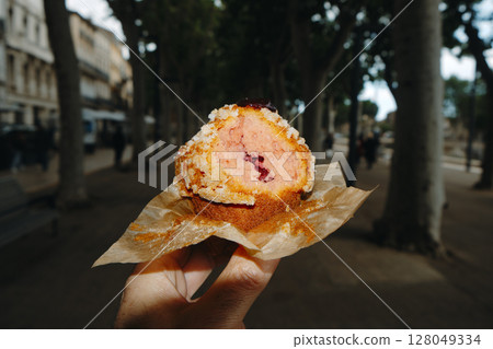 man eating a muffin filled with strawberry jam 128049334