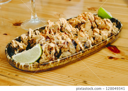 fried chipirones with lime on a wooden table 128049341