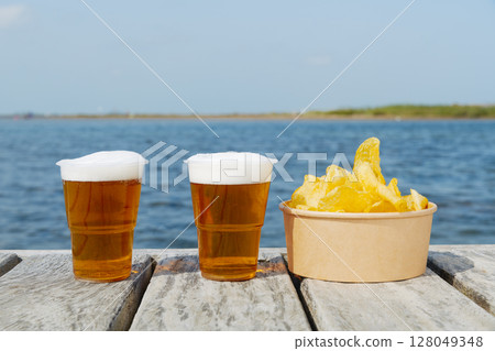 two beers and some potato chips on the dock 128049348