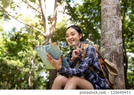 Outdoor Learning. Young woman reading a book while sitting in a serene forest. 128049451