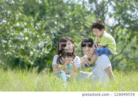 一家四口在公園的草地上玩耍 128049559