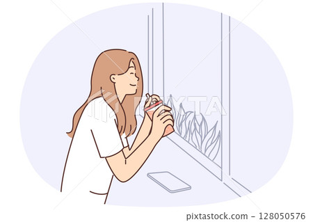 Happy woman drinking juice from disposable cup with straw sitting near window in cafe 128050576