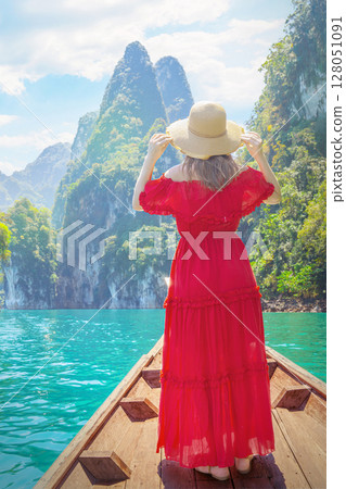 Solitude in Paradise - Woman in Red Admires Cheow Lan Lake Emerald Waters Amidst Khao Sok Limestone Cliffs from a Traditional Longtail Boat Solitude in Paradise - Woman in Red Admires Cheow Lan Lake Emerald Waters Amidst Khao Sok Limestone Cliffs from a Traditional Longtail Boat 128051091