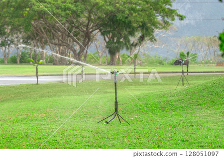 A beautiful fresh green lawn. Garden maintenance and watering lawn irrigation with garden spike 128051097