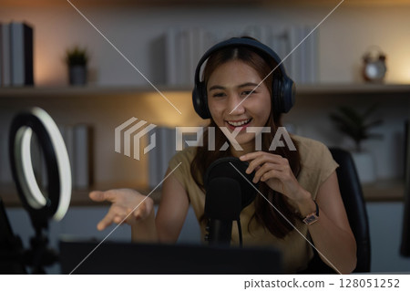 Remote Work and Digital Communication. Young woman actively participating in a video call with a microphone. 128051252