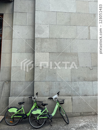 Two green bicycles by the stone wall 128051483