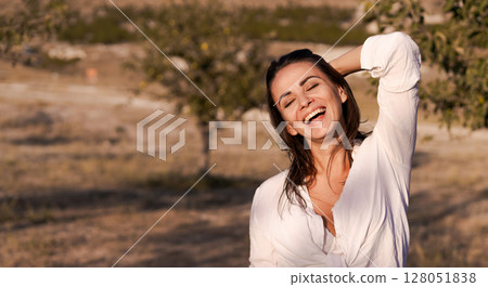 Woman is smiling and standing in a field Woman is smiling and standing in a field 128051838