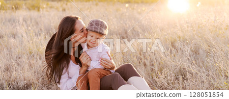 Woman is sitting in a field with a baby 128051854