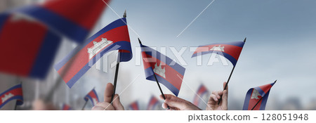 Cambodia flags in their hands on a blurred urban background 128051948