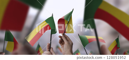 Benin flags in their hands on a blurred urban background 128051952