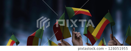 Benin flags in their hands on a blurred urban background 128051955