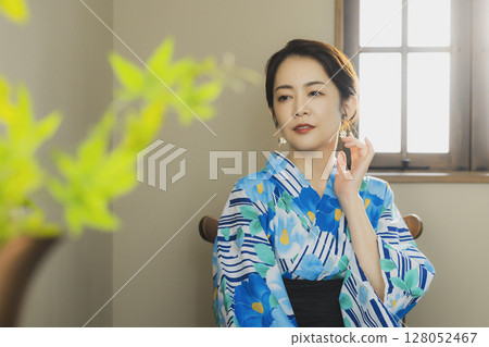 A woman in a yukata by the window 128052467