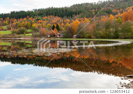 Lakeside scenery showcasing colorful autumn trees reflected on the calm water 128053412