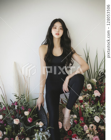Woman is sitting in front of a flower arrangement 128053506