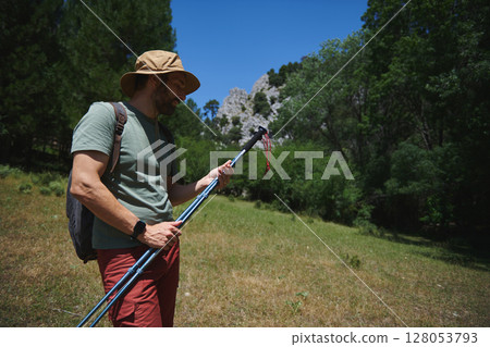 Man Preparing Hiking Gear in Serene Mountain Landscape 128053793