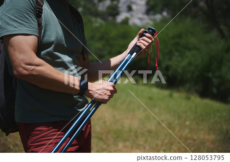 Man Hiking in Mountains Holding Trekking Poles During Summer Man Hiking in Mountains Holding Trekking Poles During Summer 128053795