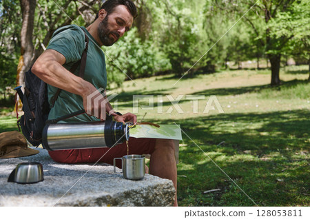 Man Relaxing in Nature Pouring Drink from Thermos with Map Man Relaxing in Nature Pouring Drink from Thermos with Map 128053811