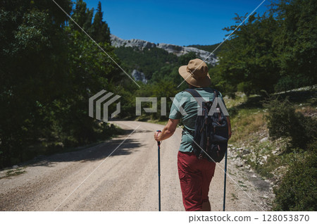 Man Hiking Along Scenic Mountain Trail On A Sunny Day 128053870