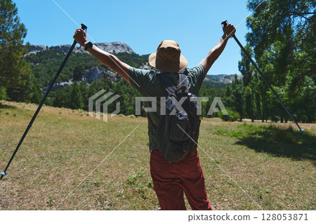 Backpacker Raising Hiking Poles Amid Stunning Mountain Landscape Backpacker Raising Hiking Poles Amid Stunning Mountain Landscape 128053871