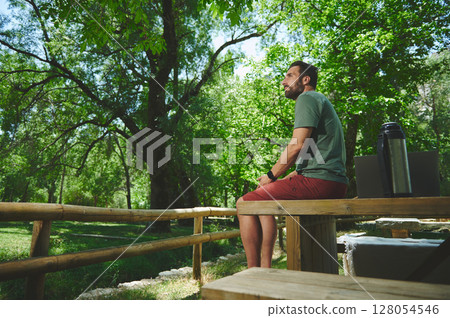 Young Traveler Enjoying a Calm Moment in a Lush Green Outdoors Setting Young Traveler Enjoying a Calm Moment in a Lush Green Outdoors Setting 128054546
