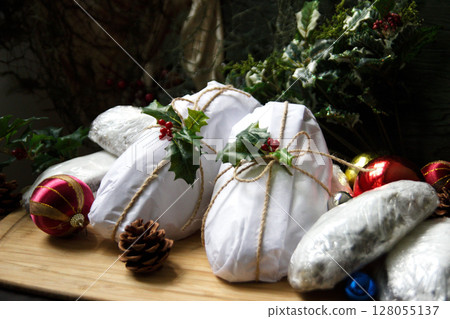 Stollen loaves wrapped in white paper with festive holly and rustic twine 128055137