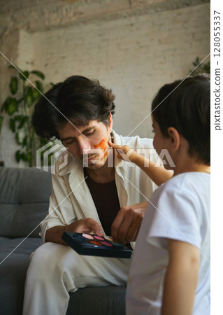 Playful fatherhood. Father and son enjoying playful face painting bonding 128055337