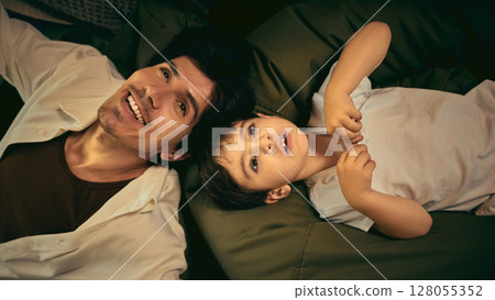 Father and son bonding on bed enjoying quality time in warm home setting Father and son bonding on bed enjoying quality time in warm home setting 128055352