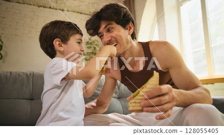Father and son enjoying breakfast together with laughter and joy on father day morning Father and son enjoying breakfast together with laughter and joy on father day morning 128055405