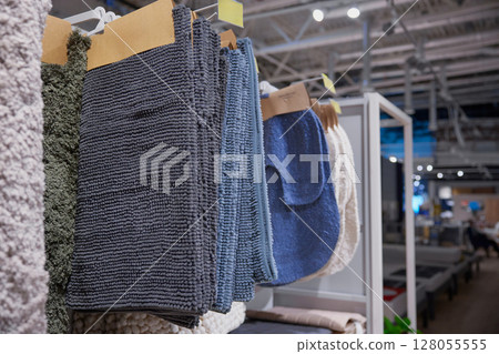 A large collection of beautiful rugs is hanging on a rack in a store A large collection of beautiful rugs is hanging on a rack in a store 128055555