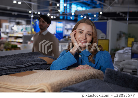 A smiling woman happily shopping in a store filled with soft and attractive textiles A smiling woman happily shopping in a store filled with soft and attractive textiles 128055577