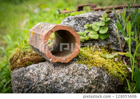 Old Clay Pipe on Moss-Covered Stone in Green Nature Setting Old Clay Pipe on Moss-Covered Stone in Green Nature Setting 128055606