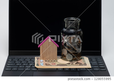 一台筆記型電腦、一張 10,000 日元鈔票、一個房屋模型和一個罐子裡的硬幣 128055995