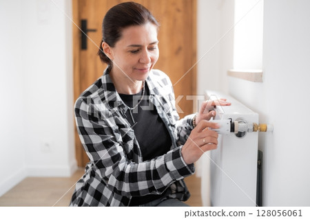 Girl Adjusting Heater Temperature By Rotating The Regulator Girl Adjusting Heater Temperature By Rotating The Regulator 128056061
