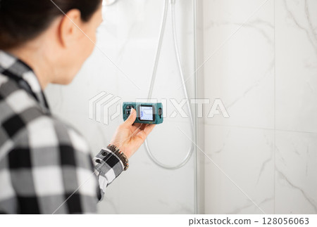 Girl Using Laser Measure In Bathroom For Choosing Washing Machine Girl Using Laser Measure In Bathroom For Choosing Washing Machine 128056063