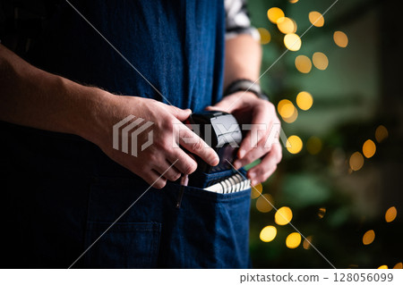 Waiter Takes The Wireless Pos Terminal From Pocket In A Restaurant At Christmas Waiter Takes The Wireless Pos Terminal From Pocket In A Restaurant At Christmas 128056099