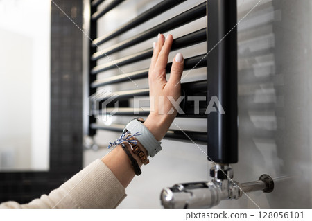 Female Hand Adjusts The Radiator Temperature And Checks The Towel Warmer's Temperature 128056101