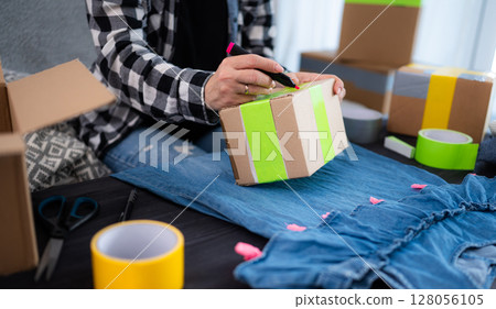 Girl Prepares A Cardboard Box For Shipping And Writes The Delivery Address Girl Prepares A Cardboard Box For Shipping And Writes The Delivery Address 128056105
